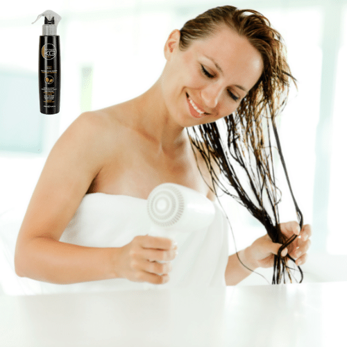 אישה מיבשת שיער עם תרסיס X10 משקם וממריץ את צמחית השיער